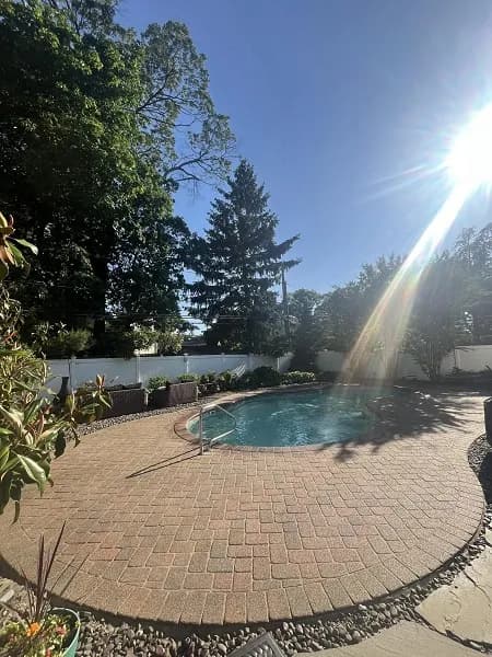 A backyard pool with clear blue water and a relaxing deck.