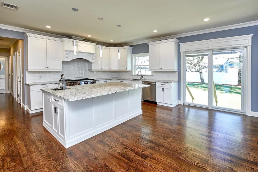 A kitchen featuring polished wooden floors and bright lighting.